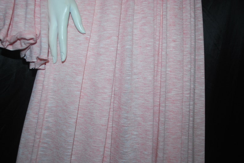 May include: A pink and white striped fabric with a subtle texture. The fabric is pleated and has a soft, flowing appearance.