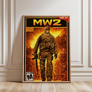 Puede incluir: Póster enmarcado con la carátula del juego "MW2". La imagen muestra a un soldado con equipo de combate sosteniendo un rifle, sobre un fondo naranja y amarillo ardiente. El póster incluye la clasificación "Mature 17+" y el texto "Action Series".