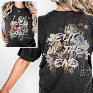 Könnte beinhalten: Dunkelgraues T-Shirt mit floralem Design und dem Text "I Tried So Hard" auf der Vorderseite. Die Rückseite des Shirts zeigt ein ähnliches florales Design mit dem Text "But In The End It Doesn't Even Matter".