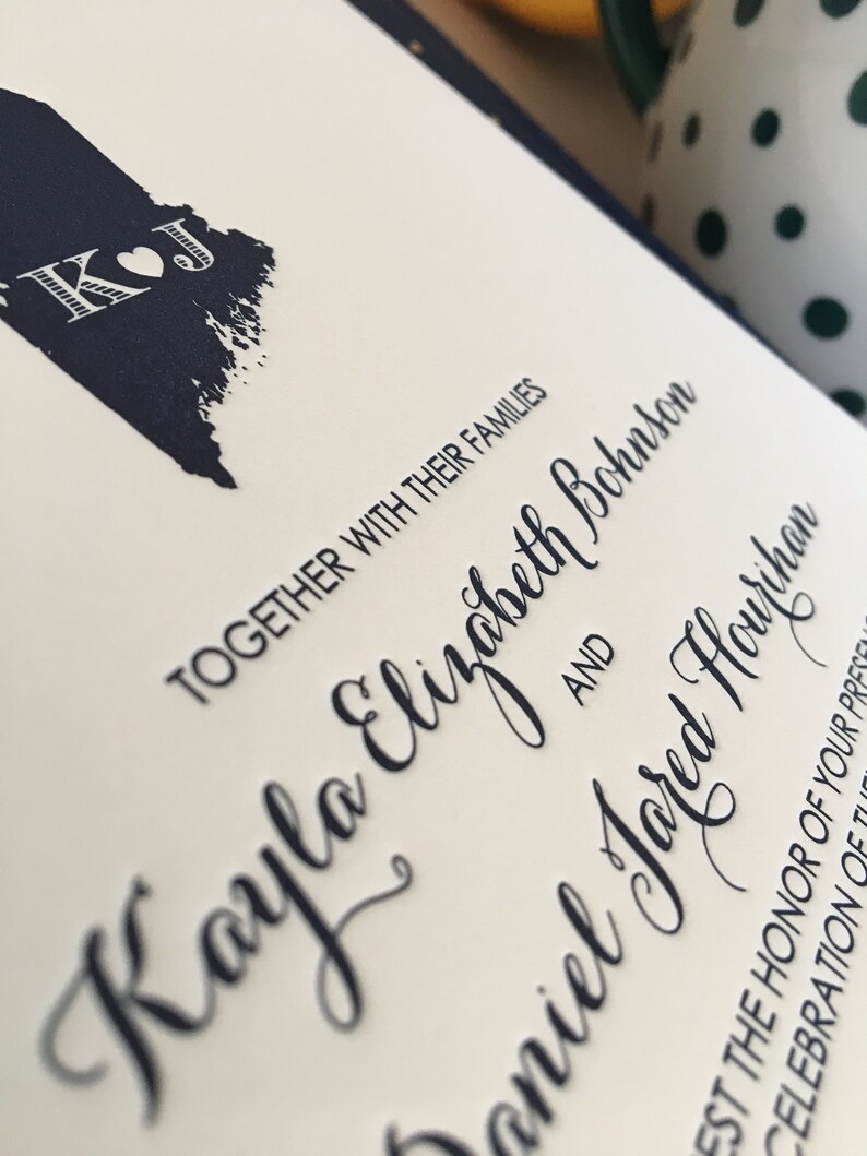 Op de afbeelding: Een huwelijksuitnodiging met donkerblauwe inkt. De uitnodiging luidt "Samen met hun families Kayla Elizabeth Bohannon en Daniel Jared Houphan".