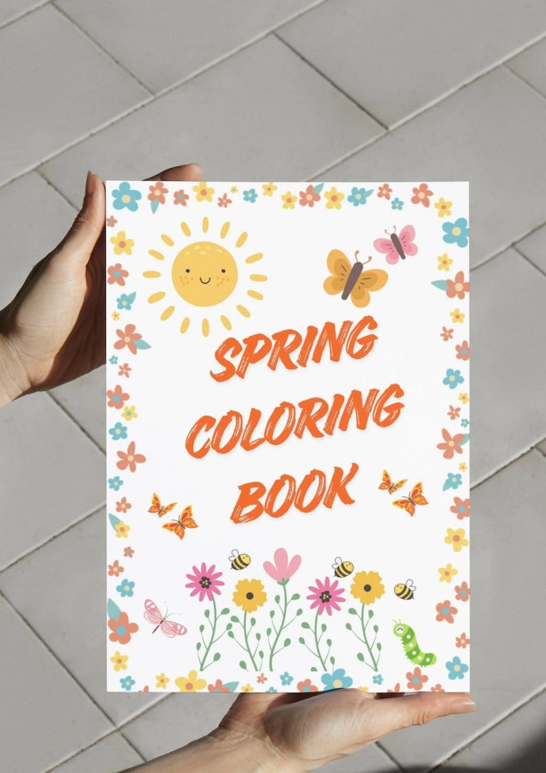 May include: A spring-themed coloring book with a white background. The cover features a smiling sun, butterflies, bees, flowers, and the words "SPRING COLORING BOOK" in orange. The book is held by a person.