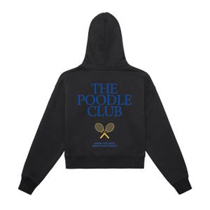 Puede incluir: Sudadera negra con capucha con el texto azul "THE POODLE CLUB" y raquetas de tenis cruzadas. La frase "SMASH THE LIMITS SERVE YOUR PASSION" está impresa debajo. La sudadera tiene un corte corto.