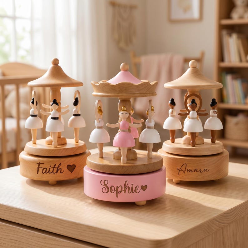 May include: Three wooden carousel music boxes featuring miniature ballerina figures. The left base is engraved with "Faith" and a heart, the center base is pink with "Sophie" and a heart, and the right base is engraved with "Amara".