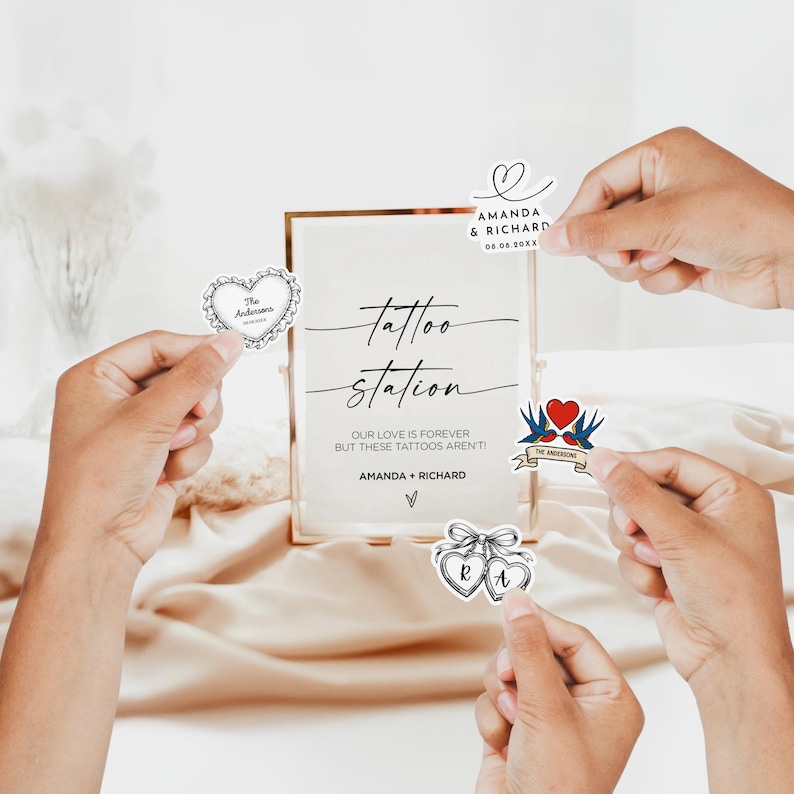 May include: A gold-framed sign with the words "tattoo station" and the names "Amanda & Richard." Several decorative stickers, including hearts and swallows, are held around the sign. The sign's text reads, "Our love is forever but these tattoos aren't!"