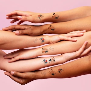 May include: Temporary tattoos featuring couples and the phrase "Love & Bliss" with a heart and floral design. The tattoos are displayed on various skin tones against a pink background.
