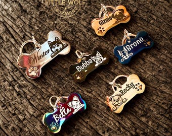 May include: A collection of bone-shaped pet tags in various colors, each with a different dog breed illustration and name. The tags are metallic with a polished finish and include names like "Winter," "Gizmo," and "Bruno." The tags are attached to a metal ring.