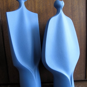 Peut inclure: Deux sculptures abstraites en c&eacute;ramique de couleur bleu clair. Les sculptures sont hautes et fines avec une surface lisse et arrondie.