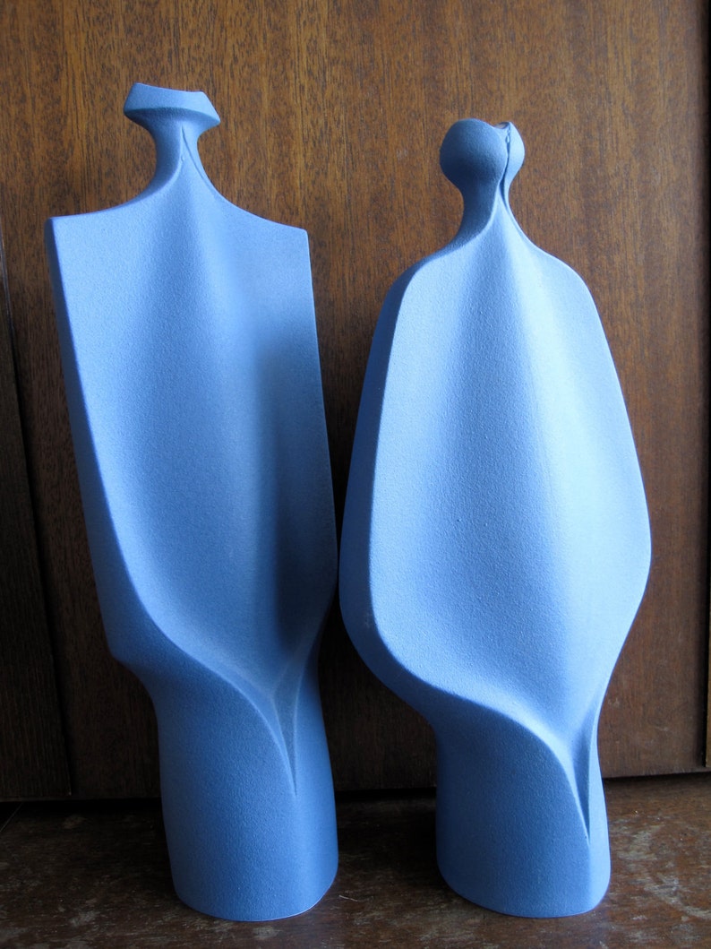 Peut inclure: Deux sculptures abstraites en c&eacute;ramique de couleur bleu clair. Les sculptures sont hautes et fines avec une surface lisse et arrondie.