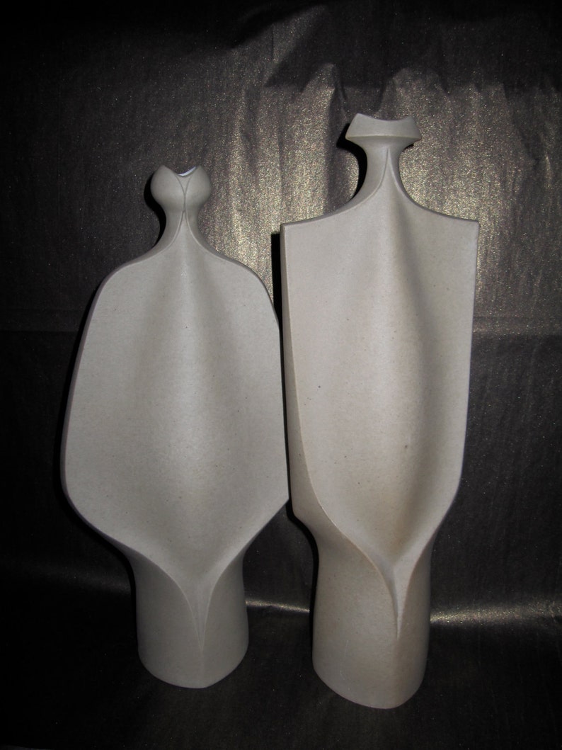 Peut inclure: Deux sculptures en c&eacute;ramique abstraites de couleur grise. Les sculptures sont hautes et fines avec une forme organique unique.