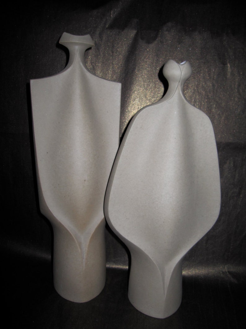Peut inclure: Deux sculptures en c&eacute;ramique de couleur grise. Les sculptures sont abstraites et ont une forme organique unique. Elles sont toutes les deux hautes et fines, avec un design incurv&eacute; et fluide.