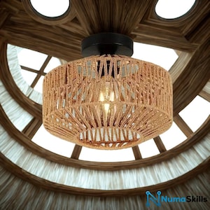 May include: A round, woven rope pendant light fixture with a black base. The light fixture is suspended from a wooden ceiling with a circular window design. The light is turned on, illuminating the woven rope shade.