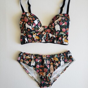 May include: Black and floral print underwear set featuring a variety of dog breeds. The bra has adjustable straps and a hook and eye fastening. The panty has a low rise and full back coverage.