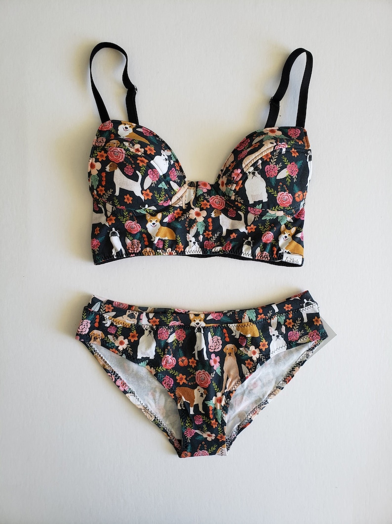 May include: Black and floral print underwear set featuring a variety of dog breeds. The bra has adjustable straps and a push-up style. The panties are a high-waisted style.