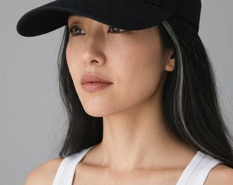 May include: A black visor featuring an embroidered design across the front panel. The embroidery depicts a row of various cats in different colors and patterns, interspersed with small pink and orange floral accents and green leaves.