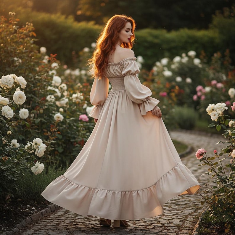 May include: A long, off-the-shoulder beige dress with long, puffy sleeves and a ruffled hem. The dress is worn in a garden setting with white and pink roses. The dress has a fitted bodice and a flowing skirt.