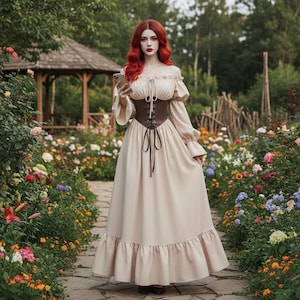 May include: A beige off-the-shoulder dress with long sleeves and a brown corset. The dress has a ruffled hem and is tied with a brown ribbon. The person is holding a phone and standing on a stone path in a garden.