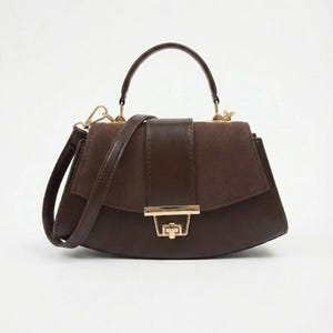 May include: A brown handbag with a top handle and a detachable shoulder strap. The bag features a flap closure with a gold-colored clasp. The bag's design includes a combination of smooth and textured materials.