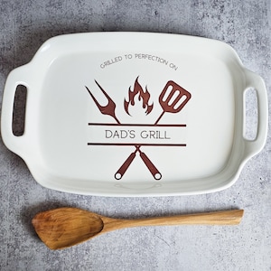 May include: White ceramic serving tray with brown handles and a brown graphic of crossed grilling tools, a flame, and the text "Grilled to perfection on Dad's Grill".