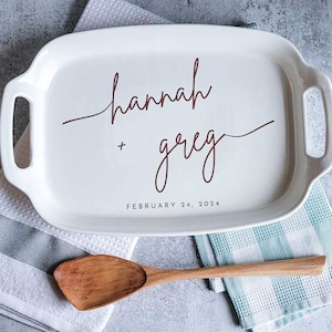 May include: White ceramic serving tray with a red cursive inscription that reads "hannah + greg" and the date "FEBRUARY 24, 2024".