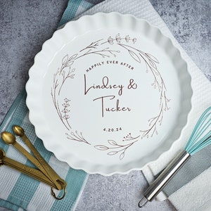 May include: White ceramic pie plate with a brown floral design and the text "Happily Ever After Lindsey & Tucker 4.20.24".