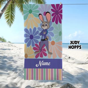 May include: A beach towel featuring Judy Hopps from Zootopia, with a floral background in pastel colors. The towel has a purple stripe at the bottom with the word "Name" and striped accents. The text "JUDY HOPPS" is on the right side.