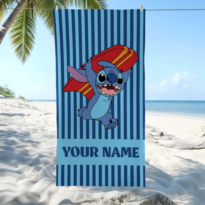 May include: Blue beach towel with vertical stripes and a cartoon character holding a red surfboard. The character is blue with large eyes and a wide grin. The text "YOUR NAME" is at the bottom of the towel.