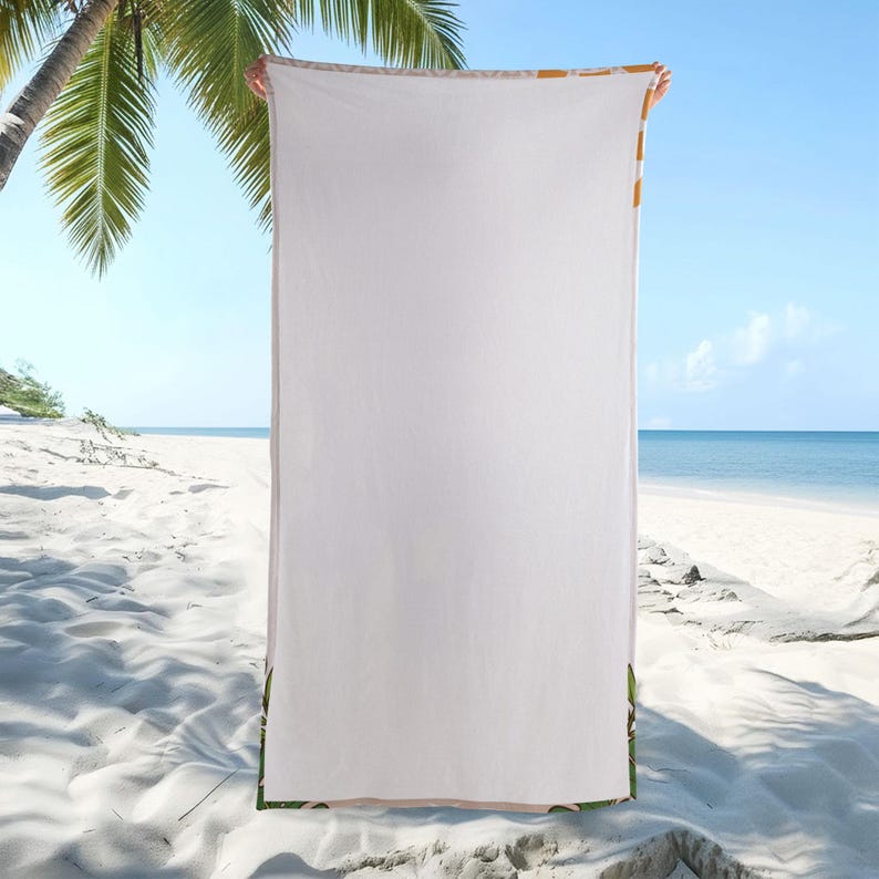 May include: A white beach towel with a tropical leaf design at the bottom and a yellow and orange border. The towel is held up against a beach background with palm trees and the ocean.