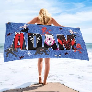 May include: Blue beach towel featuring the name "ADAM" in large, colorful letters with Spider-Man characters and web designs. The towel has a blue background with red stars and spider web patterns.