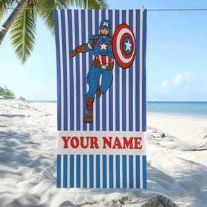以下が含まれることがあります： 青と白のストライプのビーチタオル。キャプテン・アメリカのグラフィックが描かれています。スーパーヒーローが盾を持ちながら走っている姿が描かれています。タオルには赤い文字で「YOUR NAME」と書かれています。