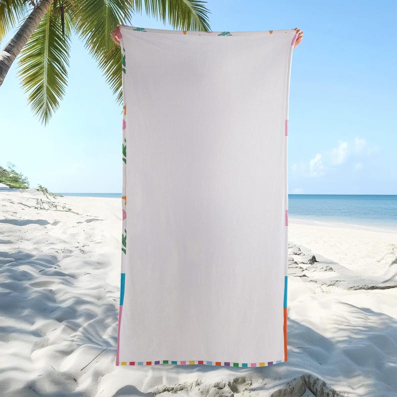 K&ouml;nnte beinhalten: Wei&szlig;es Strandtuch mit farbenfrohem Rand. Das Handtuch hat eine einfarbige wei&szlig;e Mitte mit einem lebendigen Rand mit rosa, gr&uuml;nen, blauen und orangefarbenen Streifen und Quadraten. Das Handtuch wird an einem sonnigen Strand mit Palmen und dem Meer im Hintergrund gehalten.