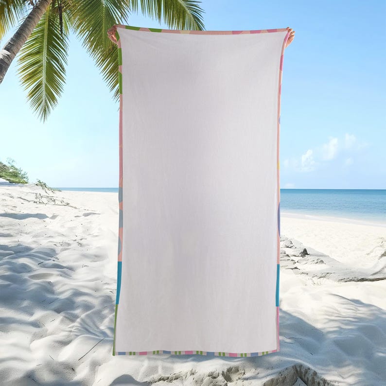 May include: A white beach towel with a colorful striped border in shades of pink, blue, green, and yellow. The towel is held up against a backdrop of a sandy beach, palm trees, and a clear blue sky.