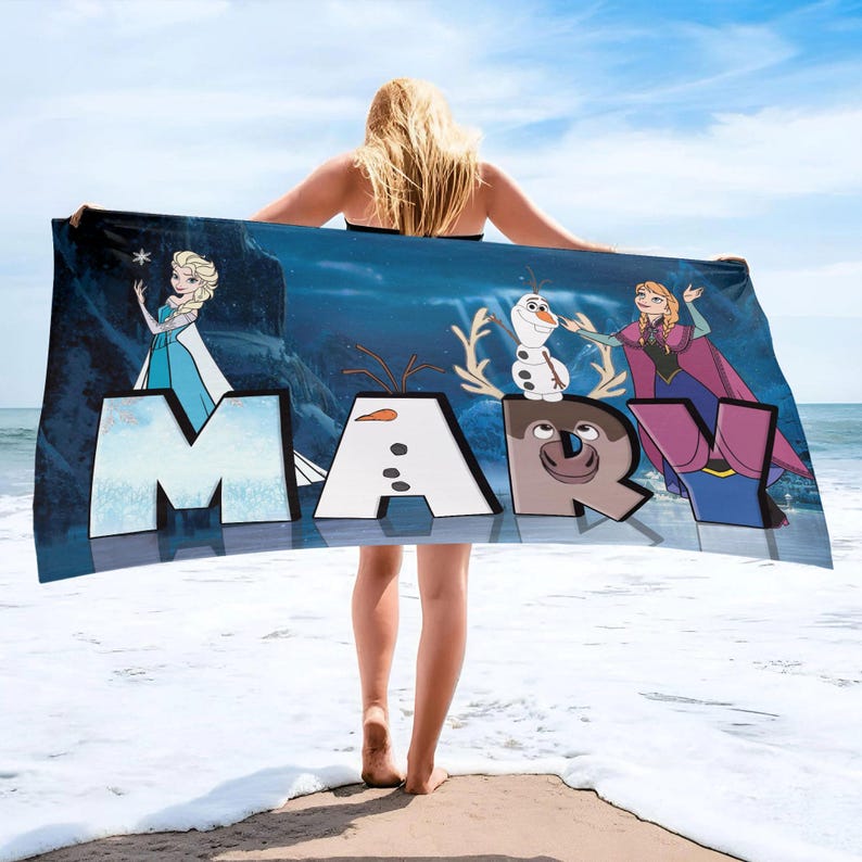 May include: A rectangular beach towel featuring a dark blue background with the name MARY in large block letters. The letters incorporate characters from the movie Frozen, including Elsa, Olaf, and Anna, along with a reindeer face on the letter R.