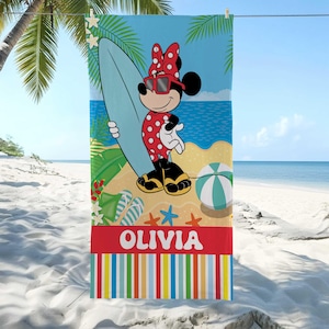 Puede incluir: Toalla de playa con Minnie Mouse con un traje de ba&ntilde;o de lunares rojos, gafas de sol y lazo, sosteniendo una tabla de surf. La toalla tiene un fondo de escena de playa con el nombre "OLIVIA" en letras blancas sobre una franja roja y rayas coloridas en la parte inferior.