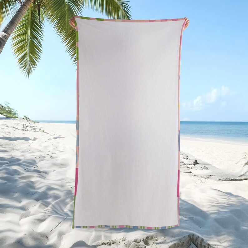 May include: A white beach towel with a colorful striped border in pink, blue, green, and yellow. The towel is held up against a backdrop of a sandy beach, ocean, and blue sky, with a palm tree in the upper left corner.