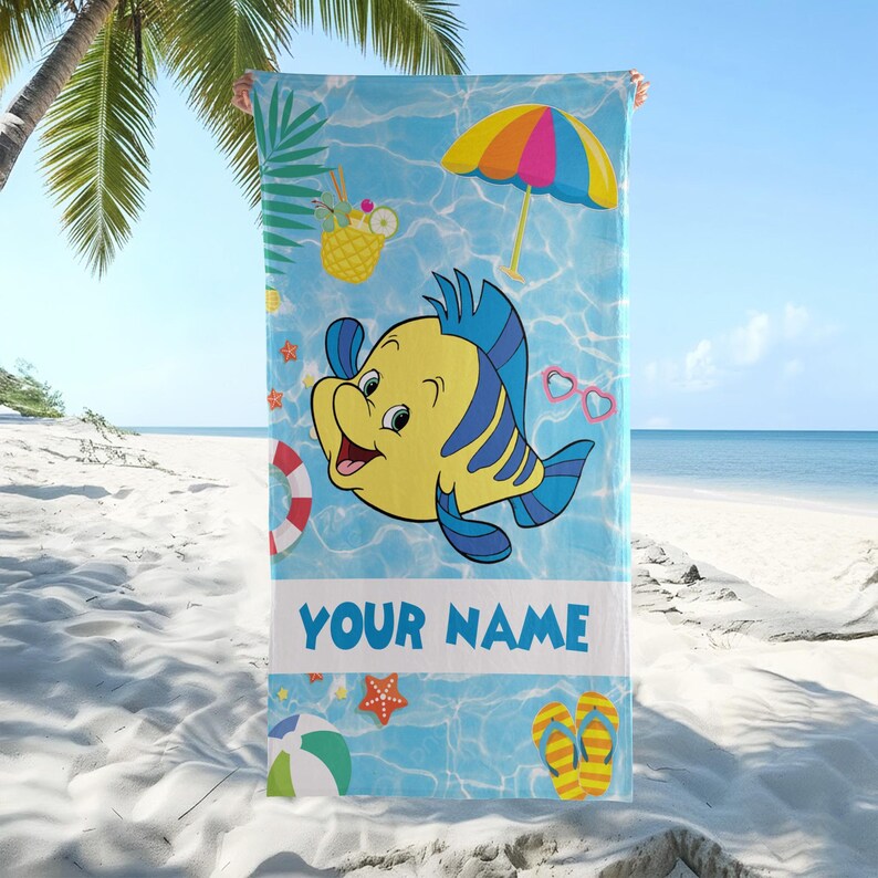Puede incluir: Una toalla de playa rectangular con fondo azul claro de agua, decorada con un pez de dibujos animados amarillo y azul, una sombrilla colorida, una bebida de pi&ntilde;a, gafas en forma de coraz&oacute;n, un salvavidas, una estrella de mar y chanclas con el texto YOUR NAME.