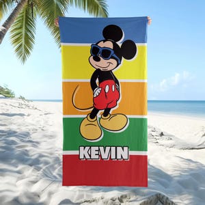 May include: A beach towel with a cartoon Mickey Mouse design wearing sunglasses, set against a striped background of blue, yellow, orange, green, and red. The name "KEVIN" is printed in white block letters at the bottom.