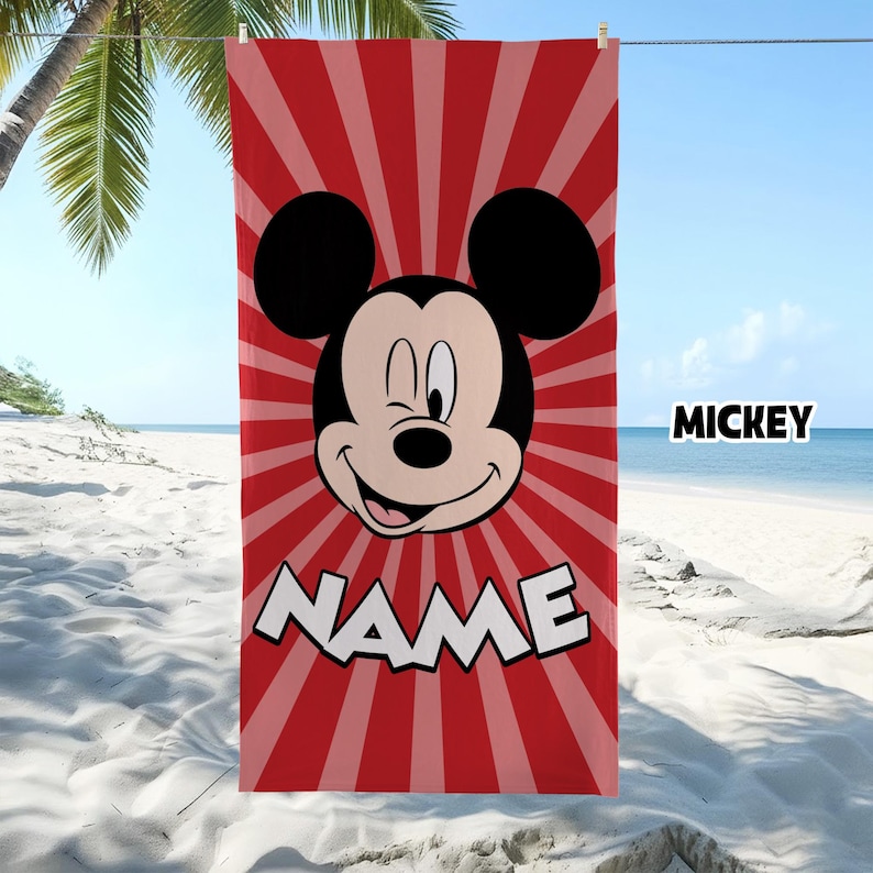 Puede incluir: Una toalla de playa rectangular con un patr&oacute;n de rayos de sol en rojo y rojo claro. El centro muestra un gr&aacute;fico de Mickey Mouse gui&ntilde;ando un ojo. Debajo del personaje, la palabra NAME est&aacute; impresa en letras blancas grandes.