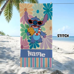 May include: A beach towel featuring the character Stitch wearing sunglasses and holding a pineapple. The towel has a floral background with the word "Name" and "Stitch" printed on it. The towel is hanging on a clothesline.