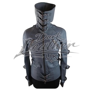 Puede incluir: Una taza de cerámica blanca con un asa negra y el texto "But First, Coffee" en negrita negra. La taza se encuentra sobre un fondo borroso, sugiriendo un ambiente acogedor.