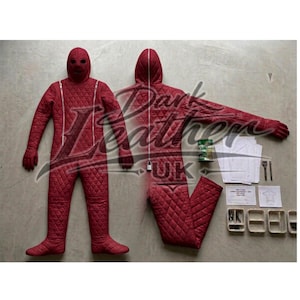 May include: A red quilted full-body suit with a hood and face covering, displayed with a matching detached leg. The suit has a diamond pattern and a zipper down the front. Additional items include a can, patterns, and tools.
