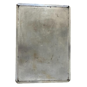 Könnte beinhalten: Ein rechteckiges, verwittertes Metallschild mit silbernem Finish. Das Schild hat einen schwarzen Rand und weist Gebrauchsspuren und Kratzer auf, was ihm ein Vintage-Aussehen verleiht. Das Metall hat eine leicht reflektierende Oberfläche.