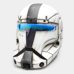 May include: White and gray helmet with a black stripe and blue visor. The helmet has a detailed design with black accents and is likely a costume or collectible item.