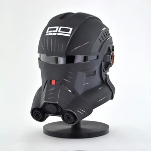 May include: A black helmet with white text and a reflective visor. The helmet has a series of vents and a red accent. It is mounted on a black stand. The overall design suggests a futuristic or sci-fi theme.