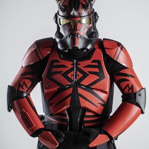 May include: A red and black costume reminiscent of a science fiction character. The helmet has horns and a black face mask with gold-tinted lenses. The armour features black geometric designs.