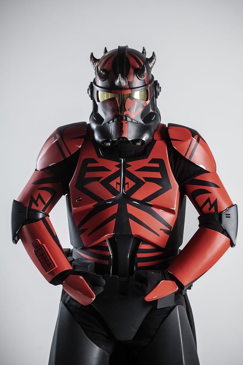 May include: A red and black costume reminiscent of a science fiction character. The helmet has horns and a black face mask with gold-tinted lenses. The armour features black geometric designs.