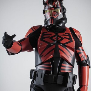 May include: A detailed costume of a character from a science fiction franchise. The armour is primarily red and black, with intricate designs and a helmet featuring horns. The character is posed with an outstretched arm.