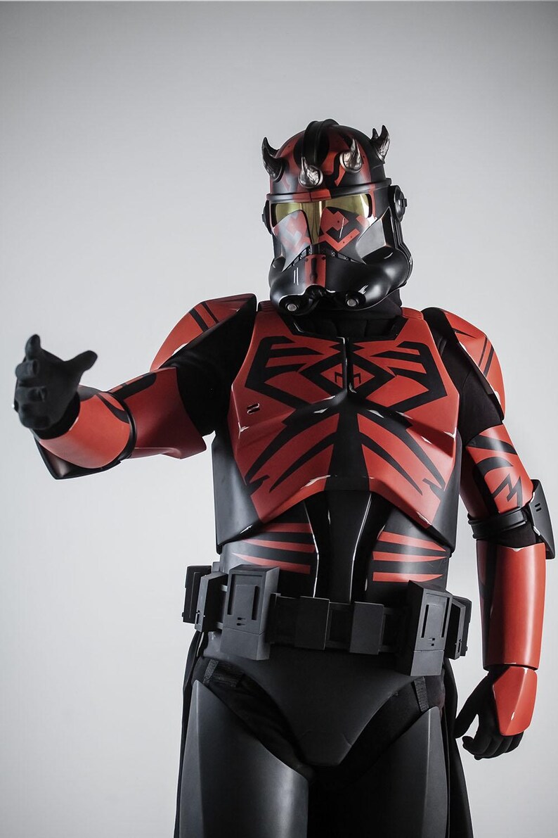 May include: A detailed costume of a character from a science fiction franchise. The armour is primarily red and black, with intricate designs and a helmet featuring horns. The character is posed with an outstretched arm.
