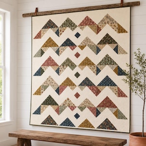 May include: A large rectangular wall quilt featuring a repeating pattern of triangular mountain-like shapes in various floral and solid fabrics. The design includes cream-colored negative space and small diamond accents in a vertical column.