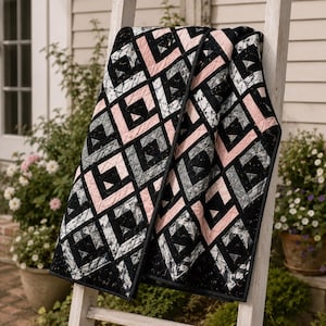 Könnte beinhalten: Eine Steppdecke mit einem geometrischen Muster aus sich wiederholenden Quadraten in Schwarz, zartem Rosa und meliertem Grau. Das Design besteht aus ineinander verschachtelten Rautenformen mit sichtbaren Steppnähten, die eine texturierte Optik erzeugen.