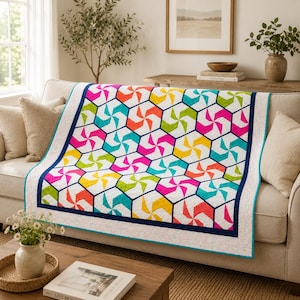 May include: A quilt featuring a repeating hexagonal pattern with vibrant pinwheel designs in shades of hot pink, turquoise, lime green, orange, and yellow. The quilt is bordered by a dark navy blue frame and a white speckled outer edge.